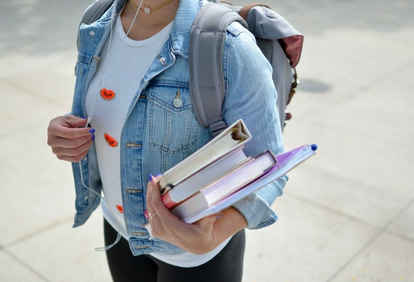 a student holding a stack of books and binders